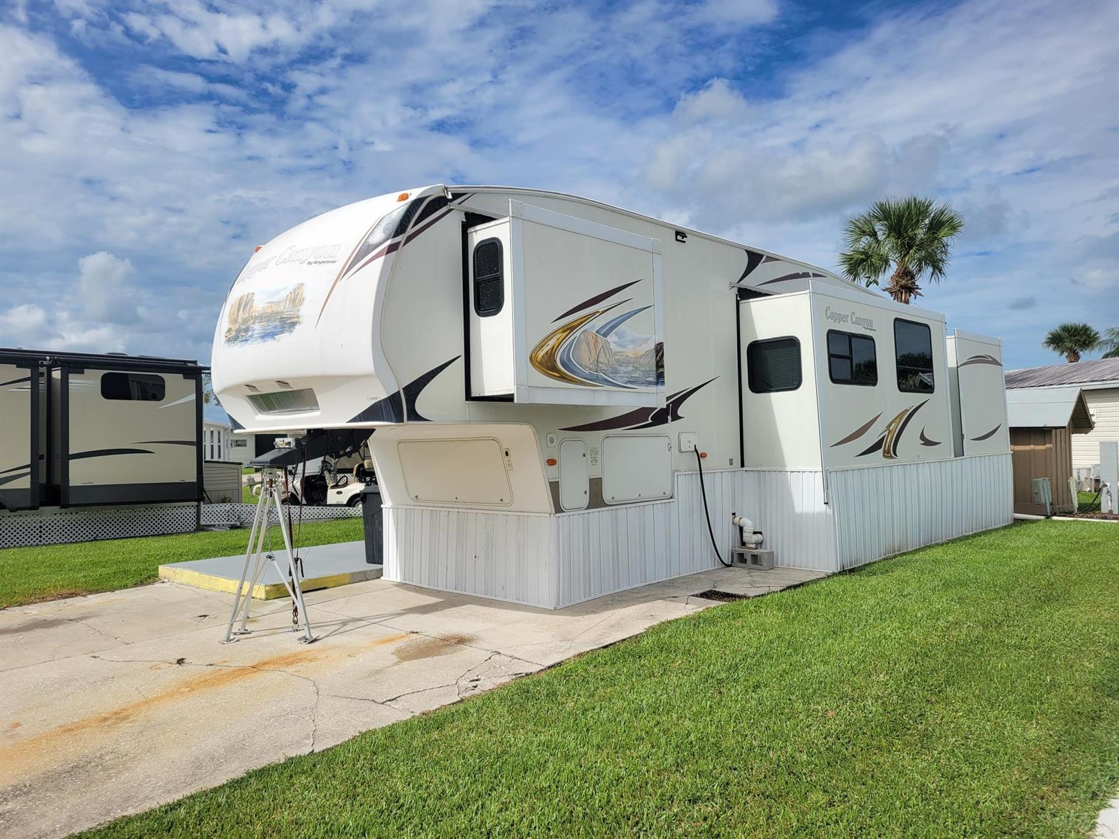 A white Keystone Copper Canyon fifth-wheel RV parked on a concrete pad with skirting installed — 6571 SE 55th Lane, Okeechobee FL 34974, OKEECHOBEE, FL