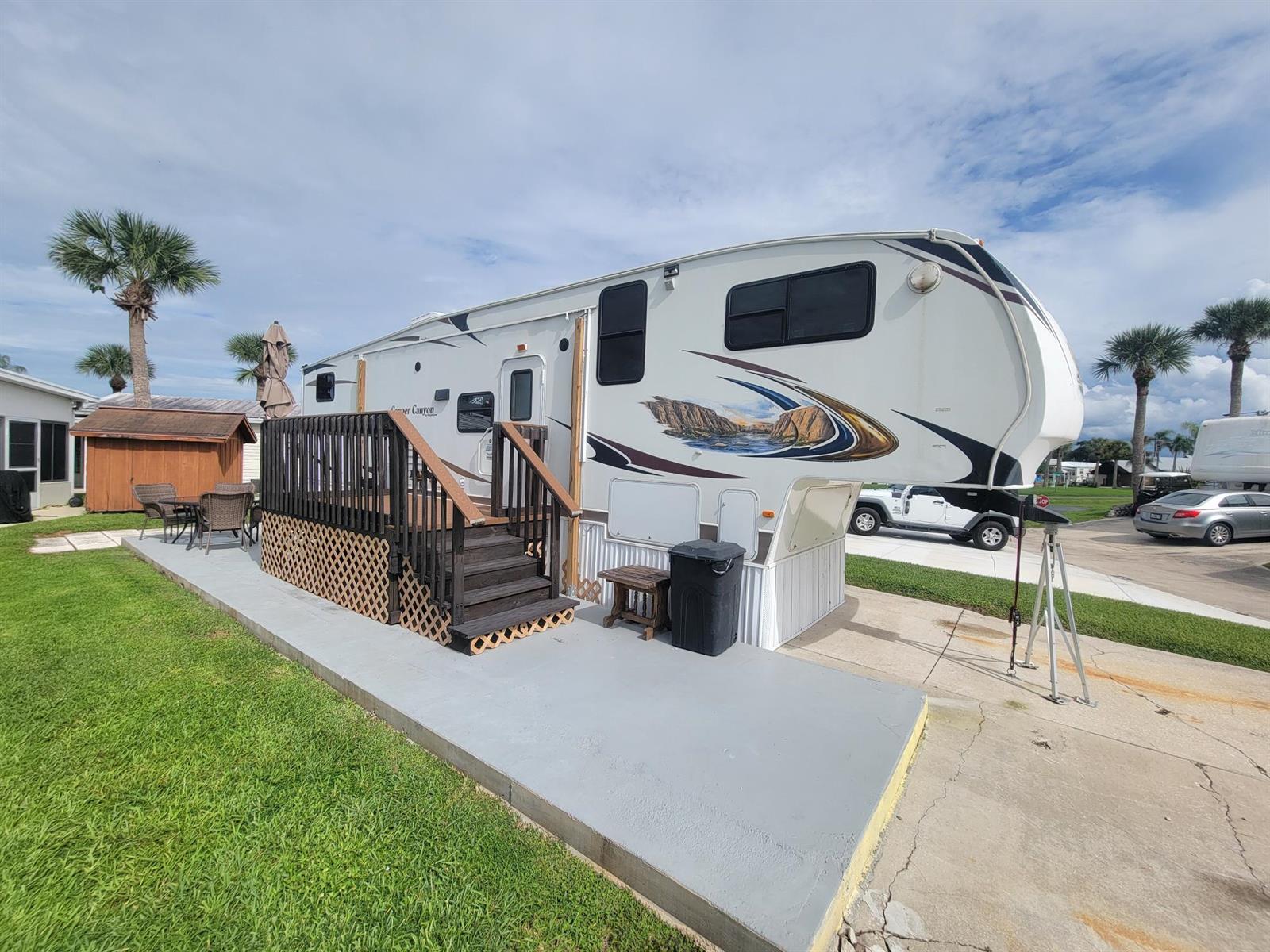 A fifth-wheel recreational vehicle parked on a concrete pad with an attached wooden deck — 6571 SE 55th Lane, Okeechobee FL 34974, OKEECHOBEE, FL
