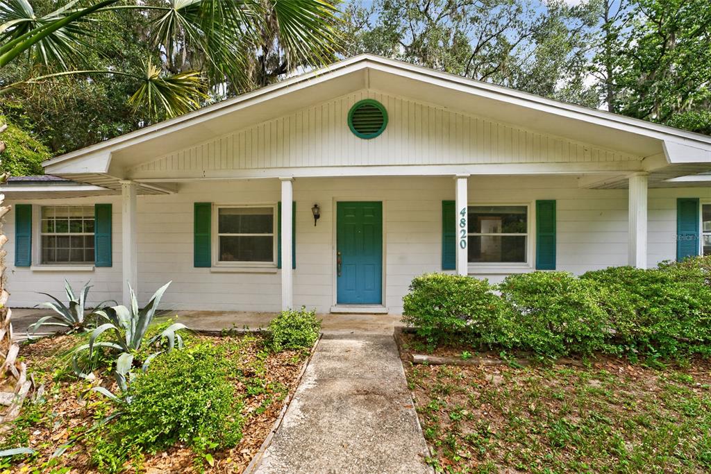 A single-story house with white siding, teal shutters, a teal front door, and a porch — 4820 NE 4TH PLACE, GAINESVILLE, FL