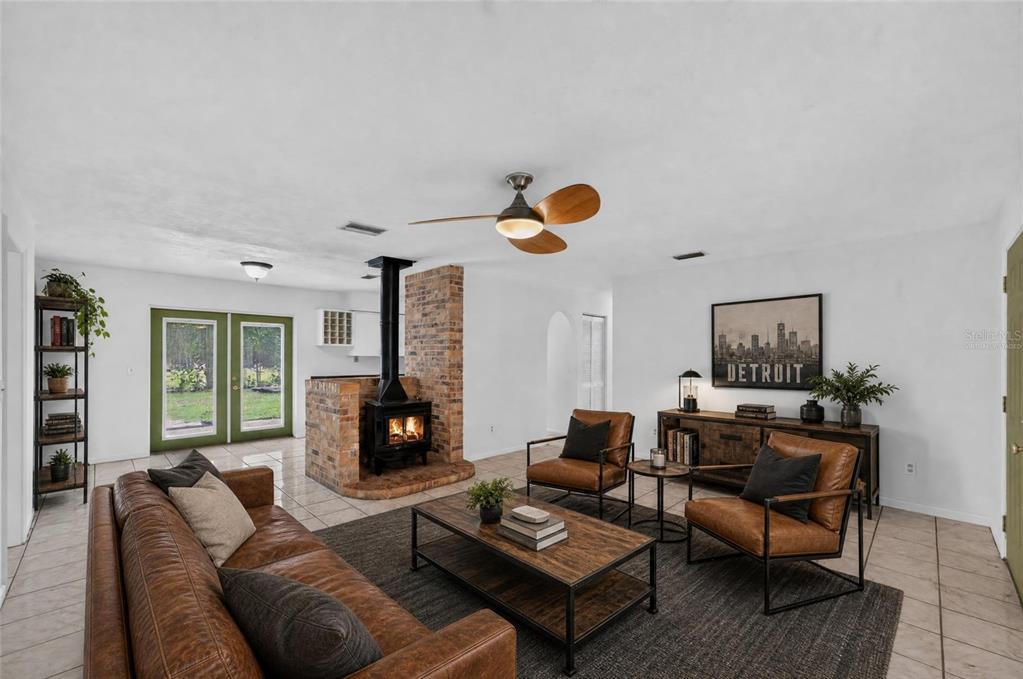 A living room features a brick fireplace, leather furniture, a ceiling fan, and tile flooring — 4820 NE 4TH PLACE, GAINESVILLE, FL