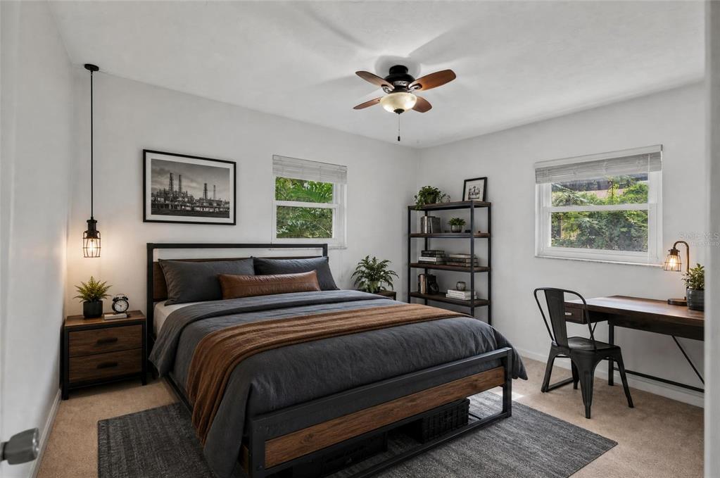 A bedroom features a bed with dark bedding, a wooden desk, and a metal bookshelf — 4820 NE 4TH PLACE, GAINESVILLE, FL