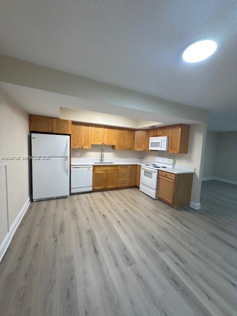 A kitchen features light wood cabinets, white appliances, and light-colored wood-look flooring — 8303 W Sample Rd # 04, Coral Springs FL 33065, CORAL SPRINGS, FL