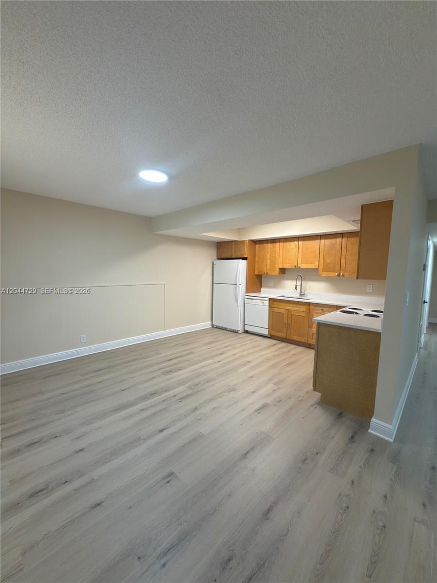This kitchen features light wood cabinets, white appliances, and light-colored wood-look flooring — 8303 W Sample Rd # 04, Coral Springs FL 33065, CORAL SPRINGS, FL