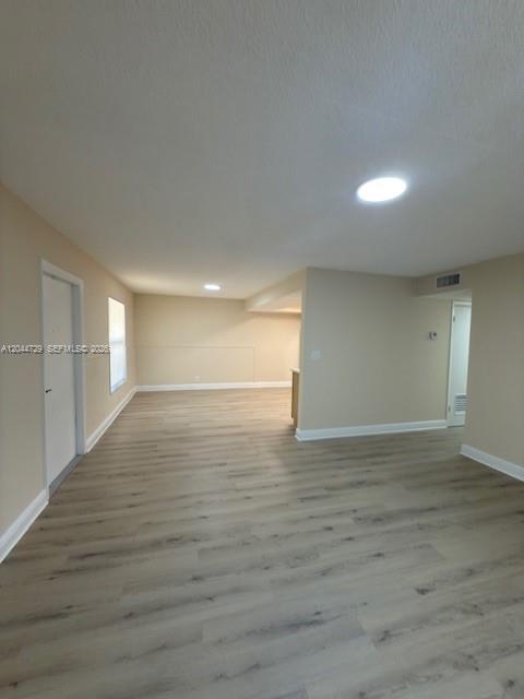 An empty room features light-colored wood-look flooring, beige walls, and recessed ceiling lighting — 8303 W Sample Rd # 04, Coral Springs FL 33065, CORAL SPRINGS, FL