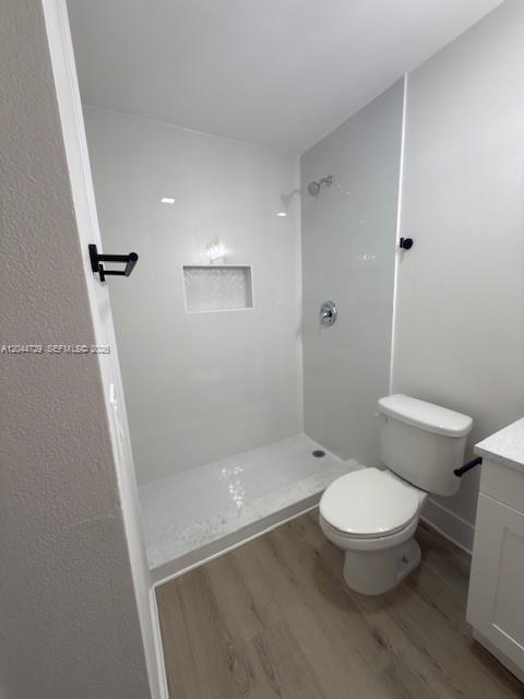 A bathroom features a walk-in shower with white tile, a toilet, and light wood-look flooring — 8303 W Sample Rd # 04, Coral Springs FL 33065, CORAL SPRINGS, FL
