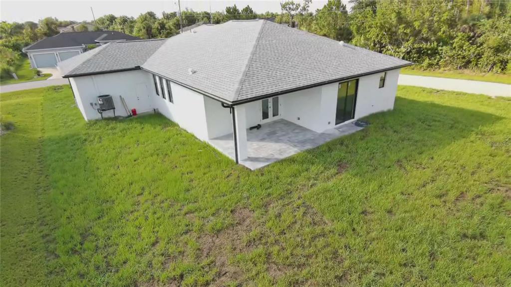 An aerial view of the back of a white house with a covered patio and lawn — 9309 ZORN STREET, PORT CHARLOTTE, FL