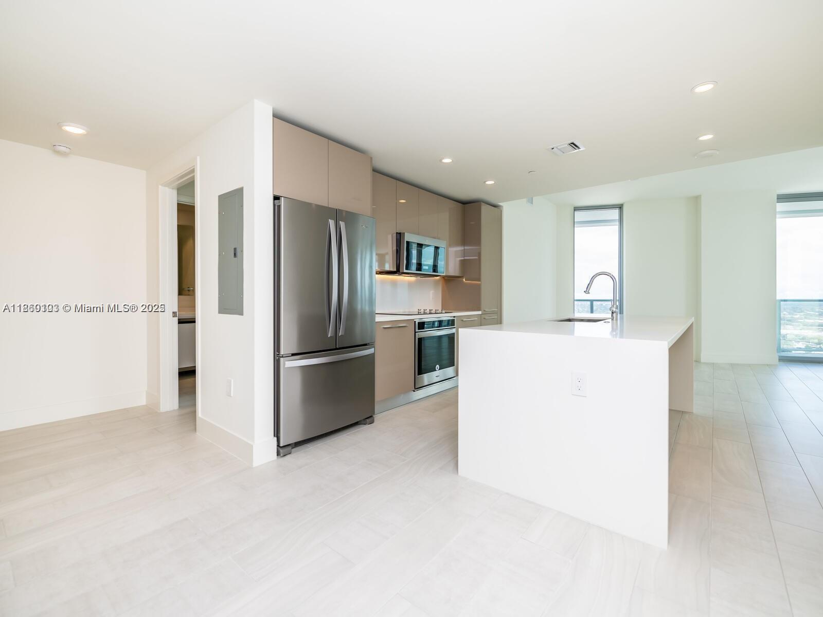 A modern kitchen features light-toned cabinetry, stainless steel appliances, and a white waterfall island — 2000 Metropica Way # 2509, Sunrise FL 33323, SUNRISE, FL