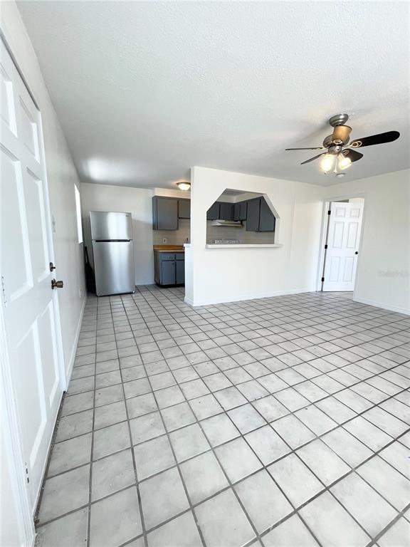 A kitchen with grey cabinets and a stainless steel refrigerator opens to a tiled room — 2916 NORTH 16TH STREET UNIT 1, TAMPA, FL