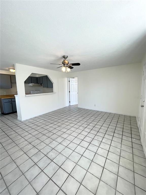 A living area with white tile floors, a ceiling fan, and a kitchen pass-through window — 2916 NORTH 16TH STREET UNIT 1, TAMPA, FL