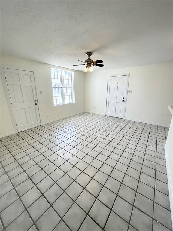 A room with white walls, a tiled floor, a ceiling fan, and two white doors — 2916 NORTH 16TH STREET UNIT 1, TAMPA, FL