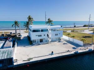 An aerial view of a white multi-story building situated next to a canal and ocean — 74560 Overseas Highway, Islamorada FL 33036, ISLAMORADA, FL