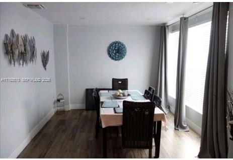 A dining room features a wooden table with chairs, light walls, and floor-length gray curtains — 8320 NW 10 Ave, Miami FL 33150, MIAMI, FL
