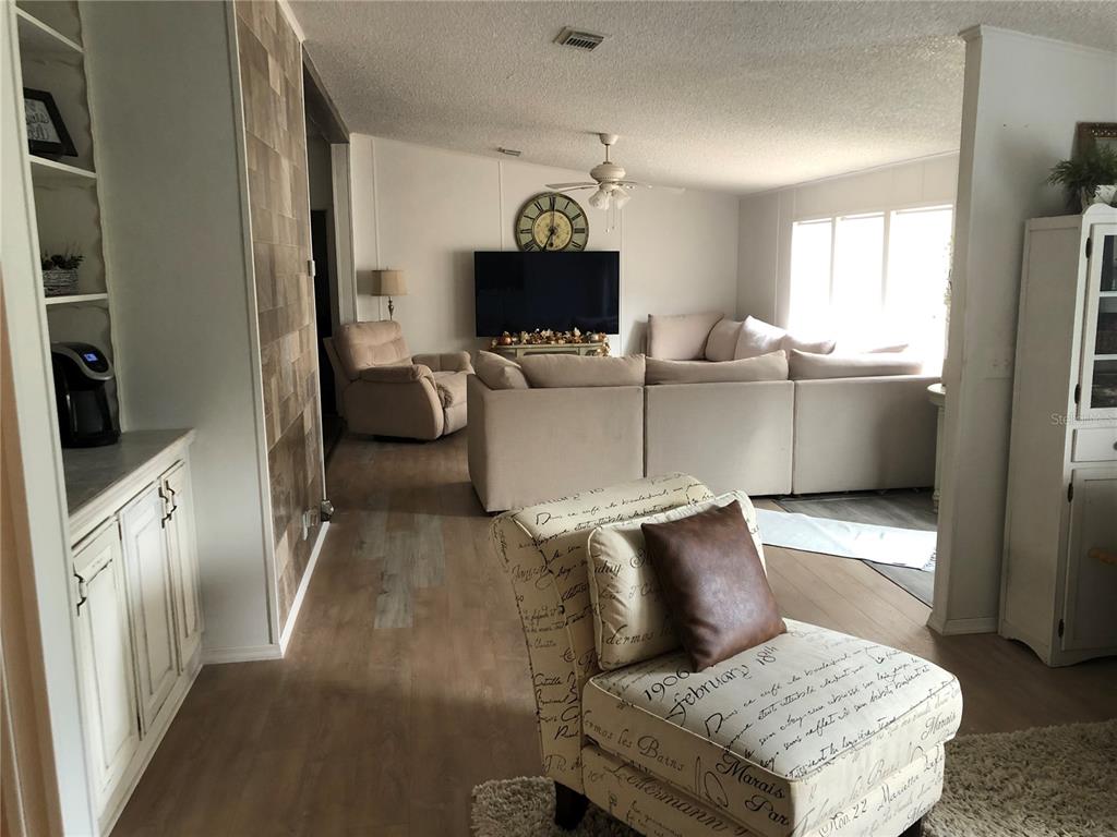 A living room features a sectional sofa, a patterned accent chair, and a tiled wall — 265 W MCCLENDON ST, LADY LAKE, FL