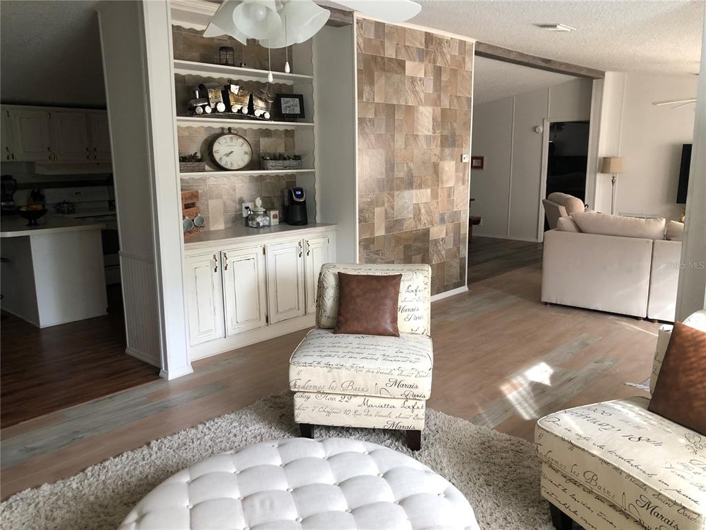 A living area features a tiled accent wall, built-in shelving, and patterned armchairs — 265 W MCCLENDON ST, LADY LAKE, FL