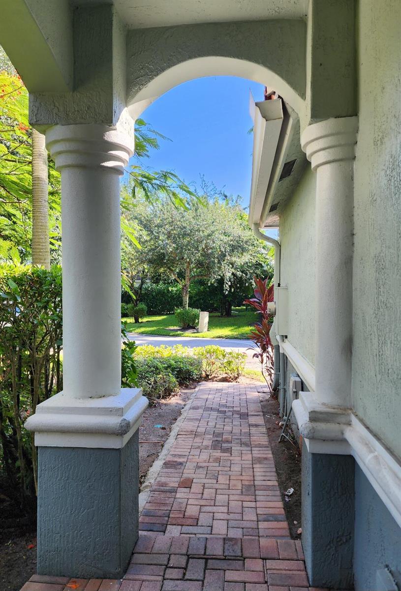 A brick walkway leads through a covered archway with two white columns toward a street — 2124 Oakmont Drive, Riviera Beach FL 33404, RIVIERA BEACH, FL