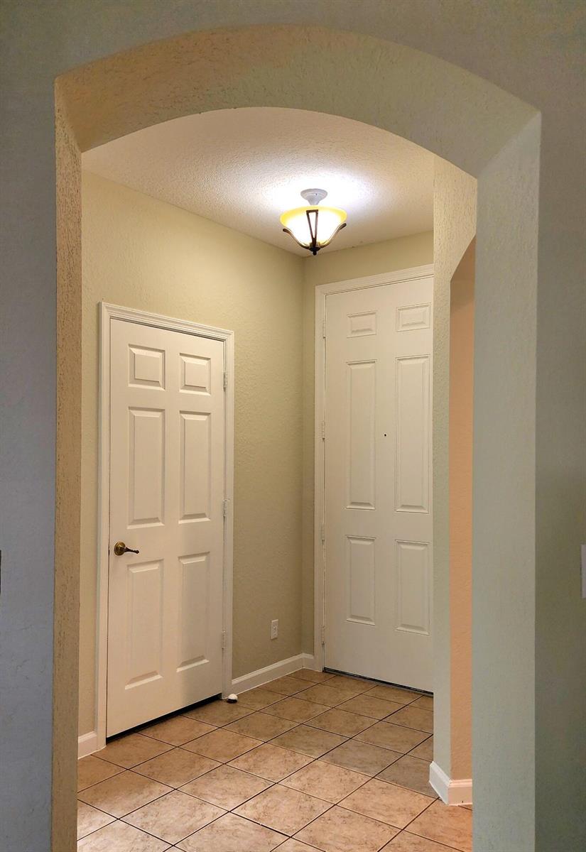 An entryway with tiled flooring, two white doors, and an arched ceiling with a light — 2124 Oakmont Drive, Riviera Beach FL 33404, RIVIERA BEACH, FL