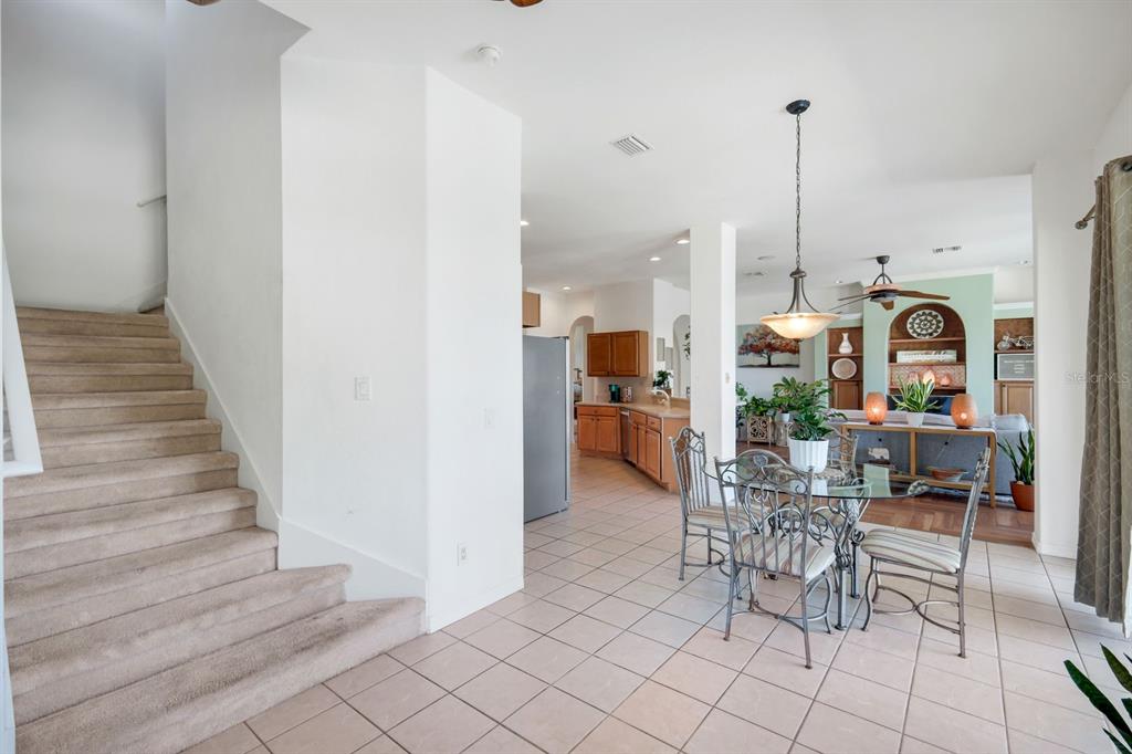 A carpeted staircase leads to an upper level next to a tiled dining and kitchen area — 1206 NW 18TH TERRACE, CAPE CORAL, FL