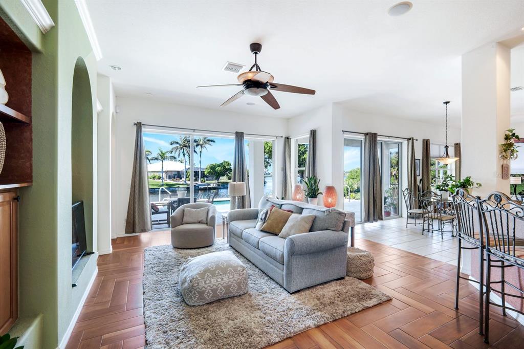 A living room with wood floors, a gray sofa, and sliding doors overlooking a canal — 1206 NW 18TH TERRACE, CAPE CORAL, FL