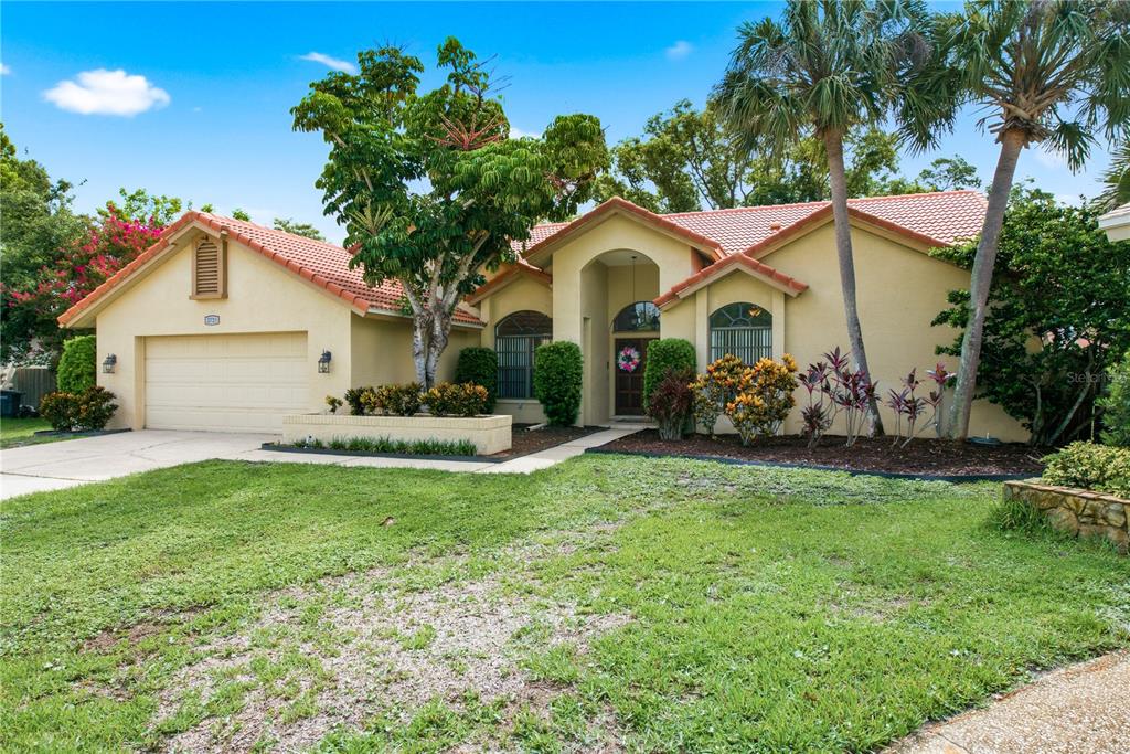 A single-story house with a tan stucco exterior, tile roof, and a two-car garage — 2729 REDFORD COURT E, CLEARWATER, FL