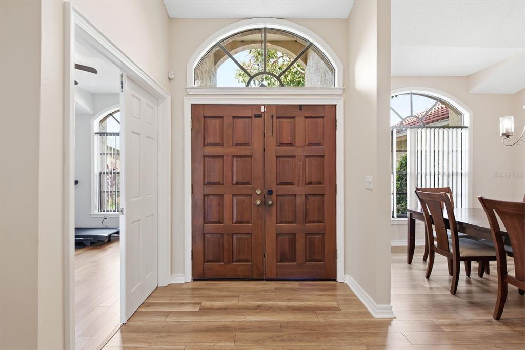 An entryway features double wooden doors, a fanlight window, and light wood-look flooring — 2729 REDFORD COURT E, CLEARWATER, FL