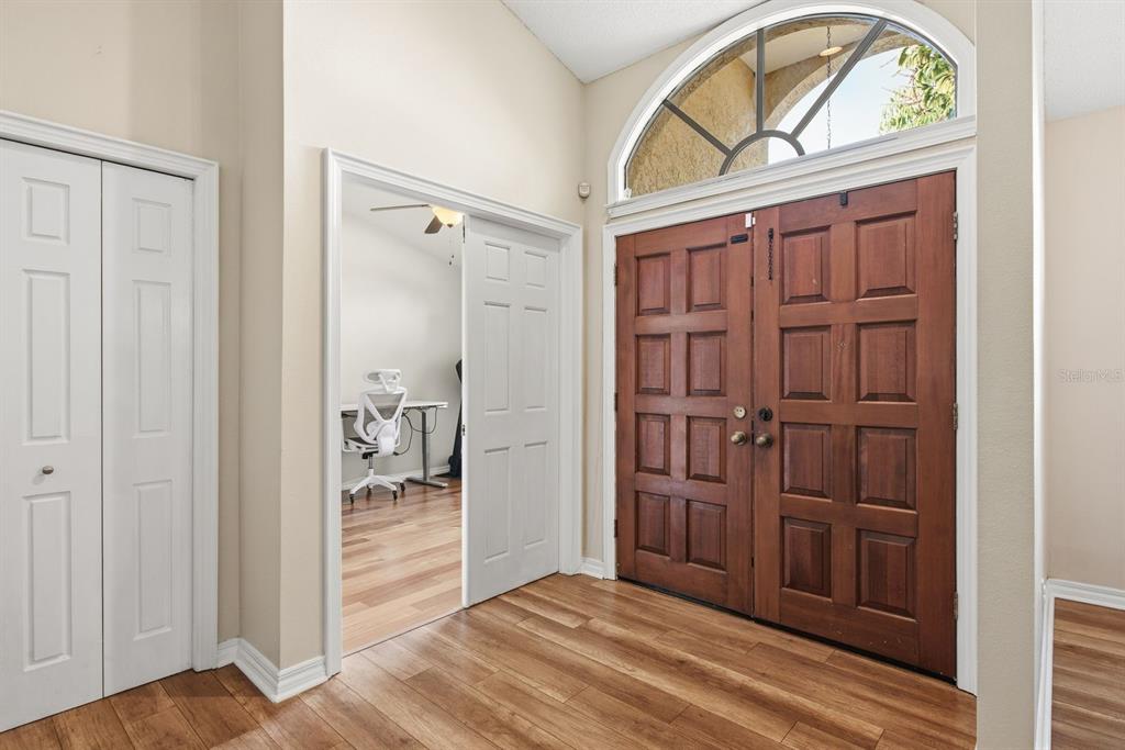 An entryway features wood-look flooring, double wooden front doors, and a white-paneled closet door — 2729 REDFORD COURT E, CLEARWATER, FL