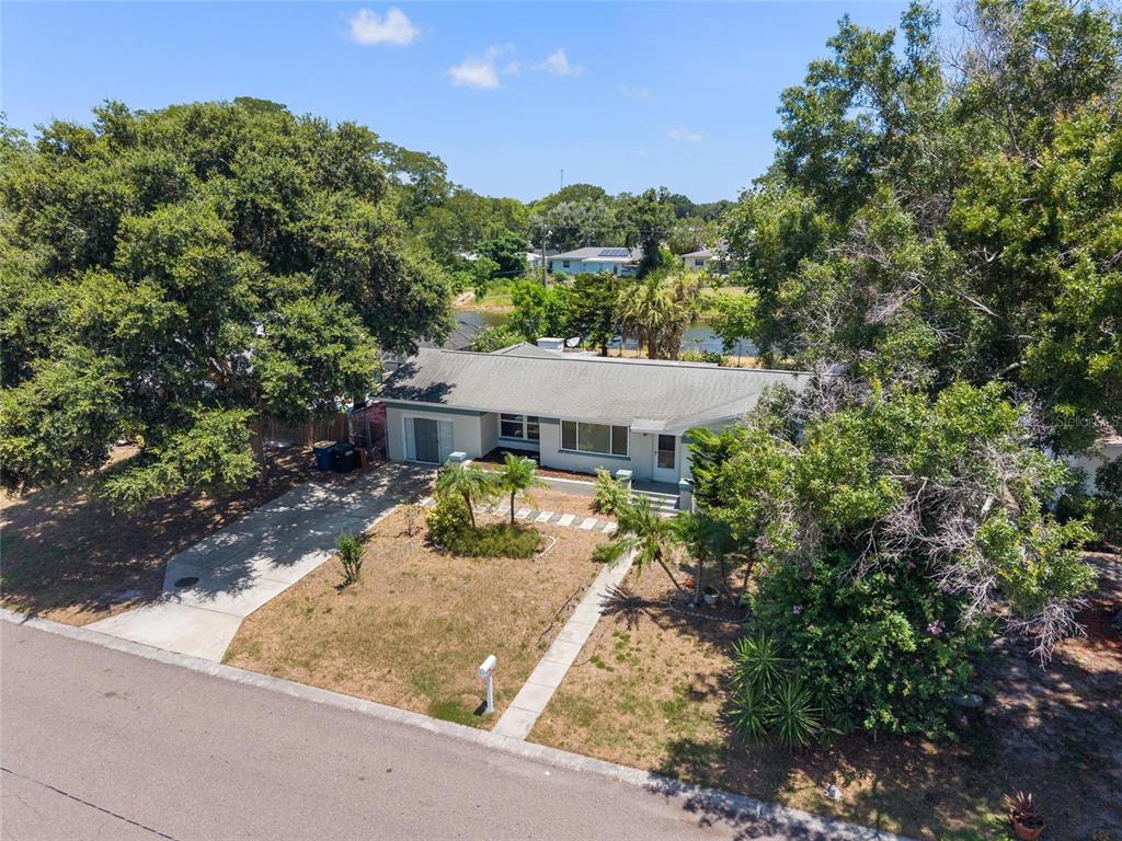 An aerial view shows a single-story house with a driveway, lawn, and surrounding trees — 1428 PINEBROOK DRIVE, CLEARWATER, FL