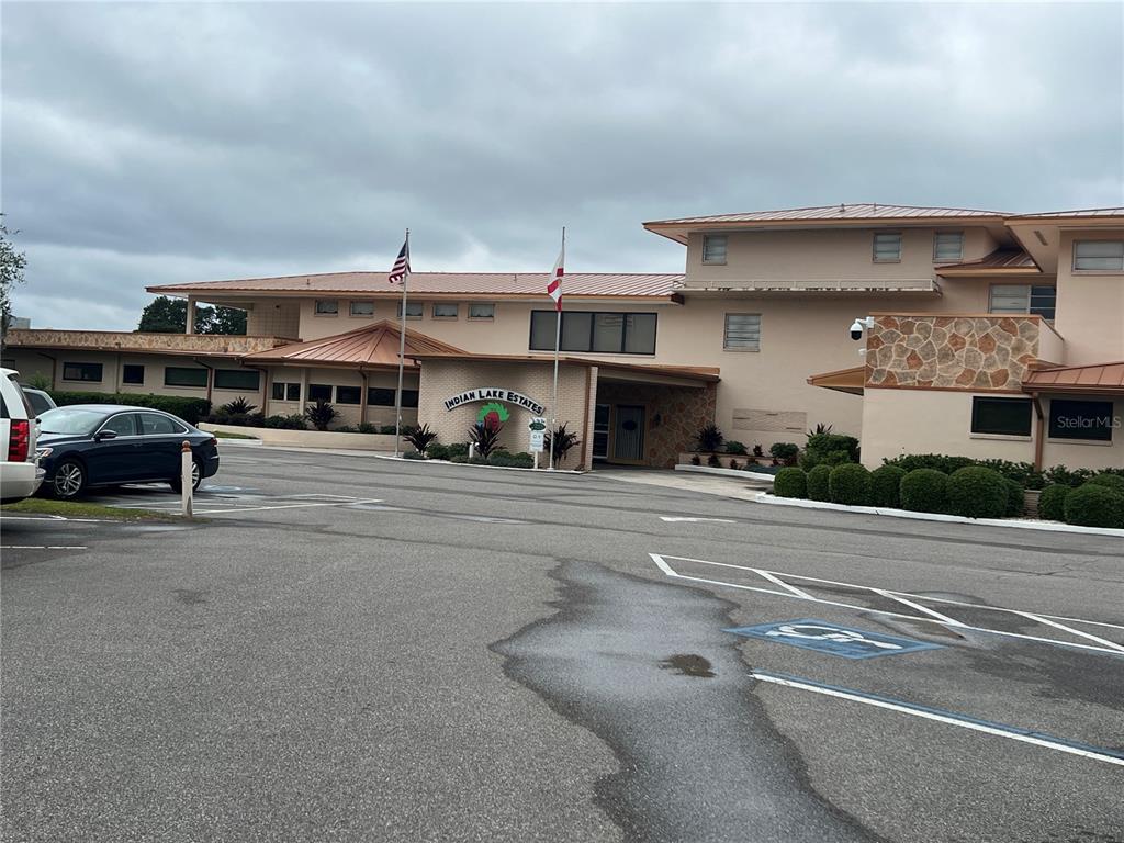A multi-story building with a tan exterior and a metal roof features a parking lot — 506 MAGNOLIA DRIVE, INDIAN LAKE ESTATES, FL