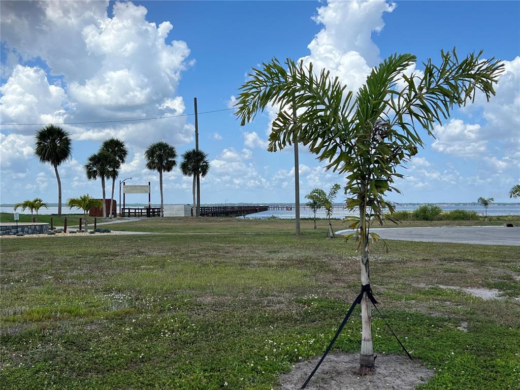 A grassy park area features several palm trees and a wooden pier extending into water — 506 MAGNOLIA DRIVE, INDIAN LAKE ESTATES, FL