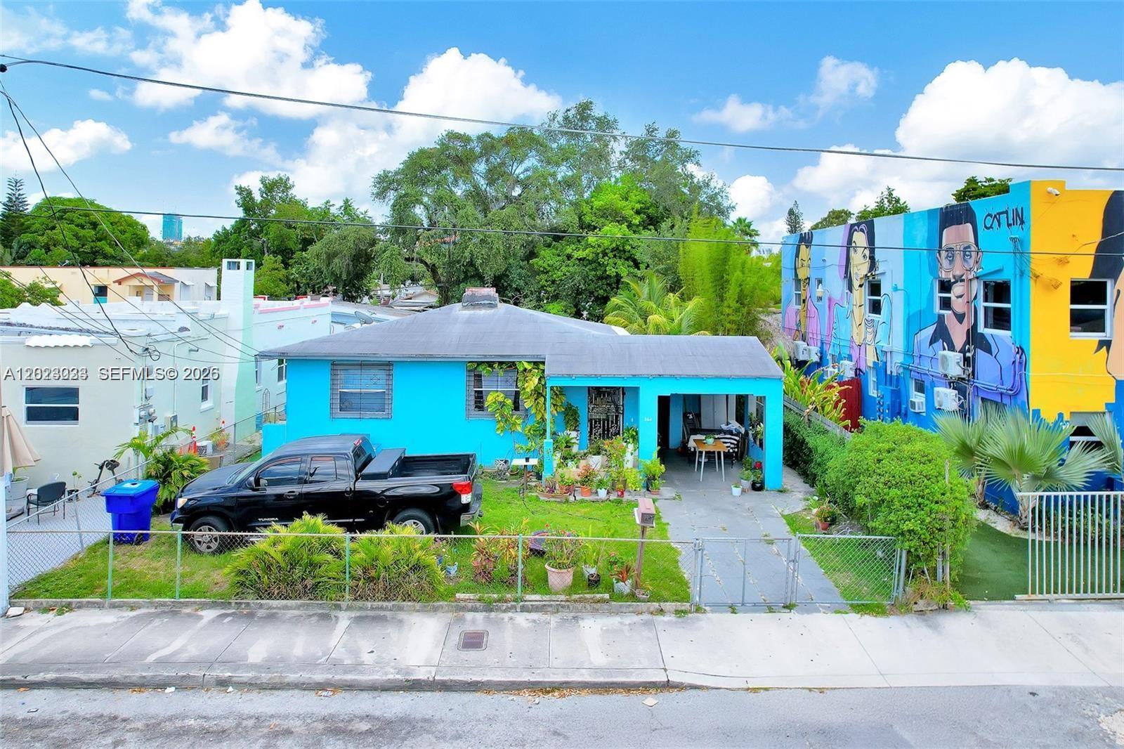 A bright blue house with a front porch sits between a white building and a mural-covered structure — 266 NW 32nd St, Miami FL 33127, MIAMI, FL