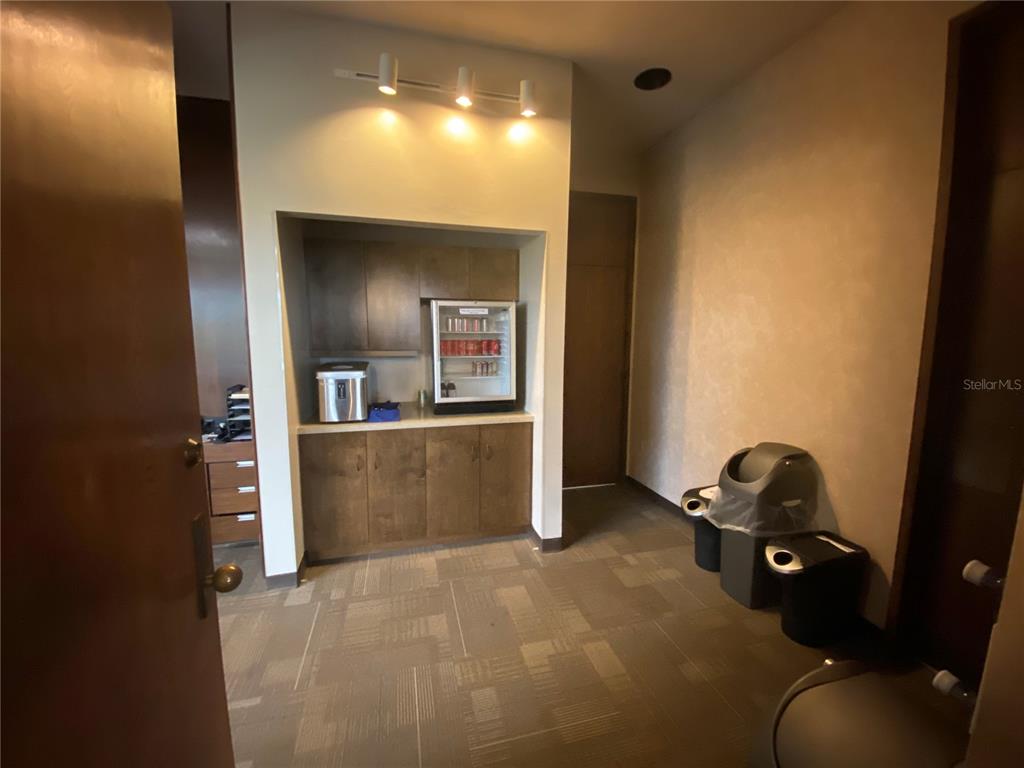 A small office break area features wood cabinetry, a beverage refrigerator, and carpeted flooring — 2815 NW 13TH STREET 4th Floor, GAINESVILLE, FL