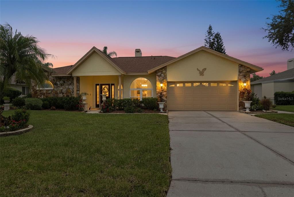 A single-story house with a stone facade, a two-car garage, and a manicured front lawn — 23427 PINE LAKE STREET, LAND O LAKES, FL