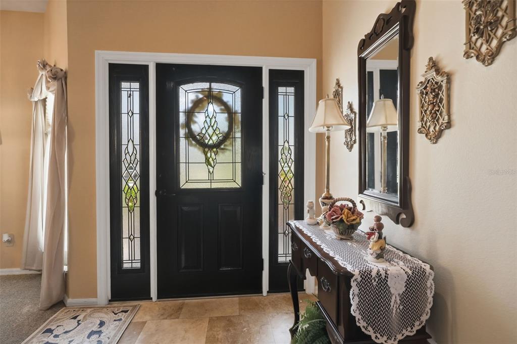 An entryway features a black front door with sidelights, tile flooring, and a wooden console table — 23427 PINE LAKE STREET, LAND O LAKES, FL