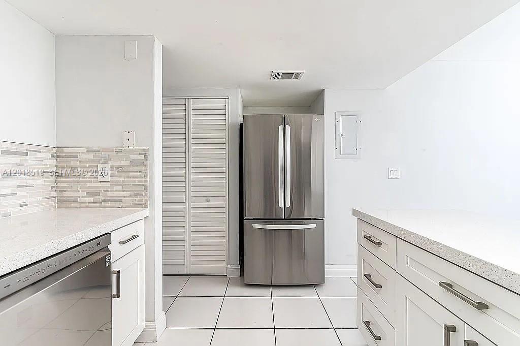 A kitchen features white cabinets, stainless steel appliances, and light-colored tile flooring — 1931 Sabal Palm Dr # 301, Davie FL 33324, DAVIE, FL