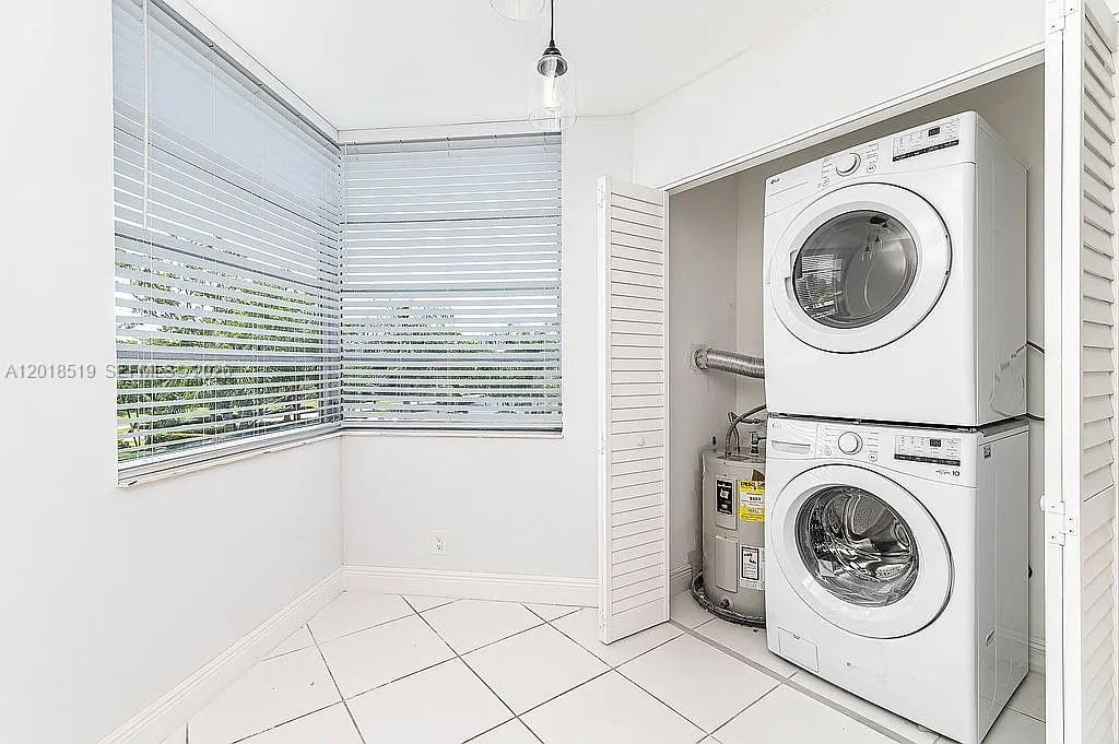A laundry room features a stacked washer and dryer, a water heater, and tiled floors — 1931 Sabal Palm Dr # 301, Davie FL 33324, DAVIE, FL