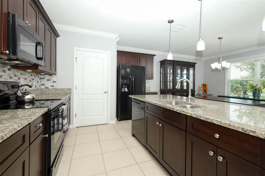 A dining room features a dark wood table, a chandelier, and a sliding glass door — 3802 BISHOP LANDING WAY, ORLANDO, FL