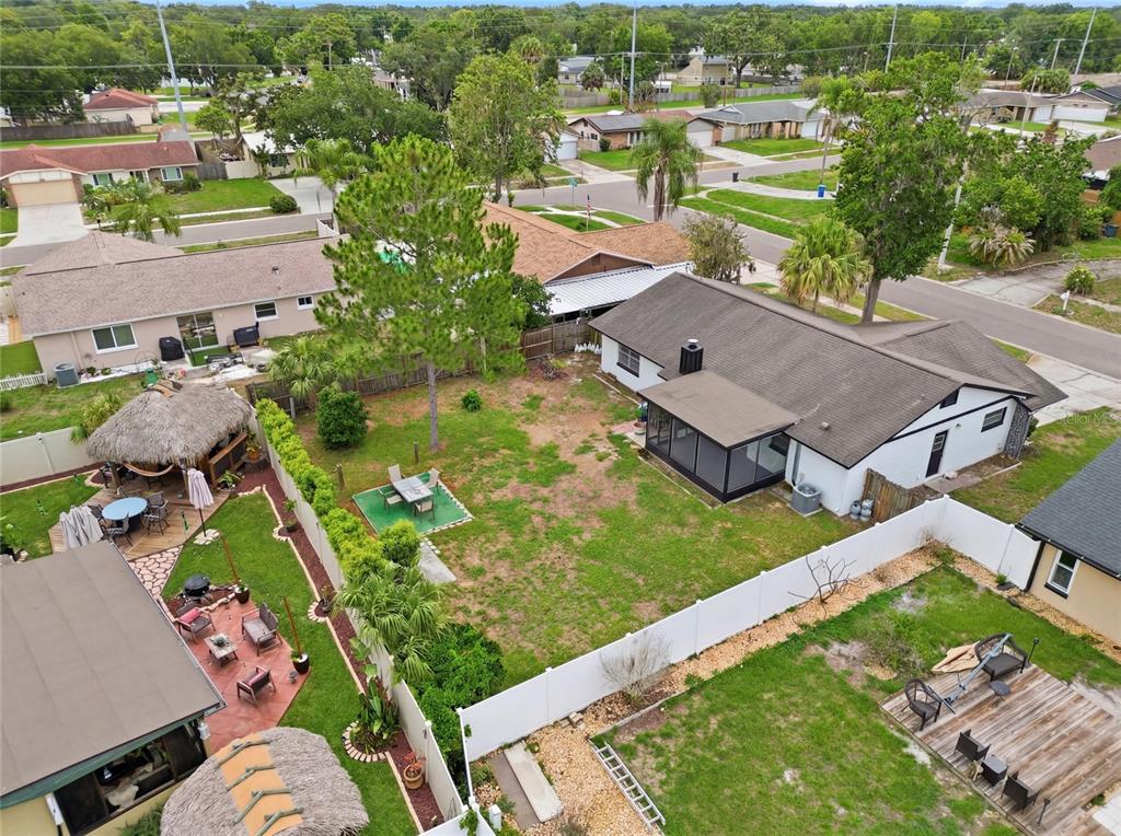 An aerial view shows a residential backyard with a patio, tiki hut, and white fencing — 804 CENTERWOOD COURT, BRANDON, FL