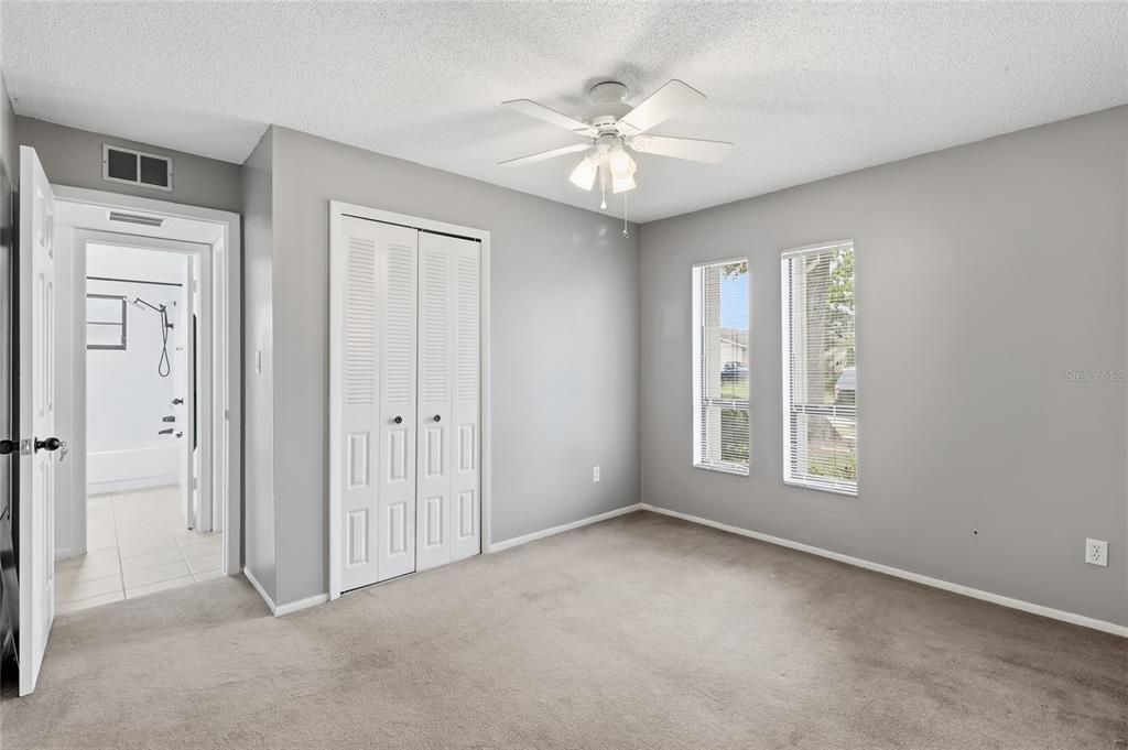 A bedroom with gray walls, beige carpet, a ceiling fan, and an attached bathroom — 804 CENTERWOOD COURT, BRANDON, FL