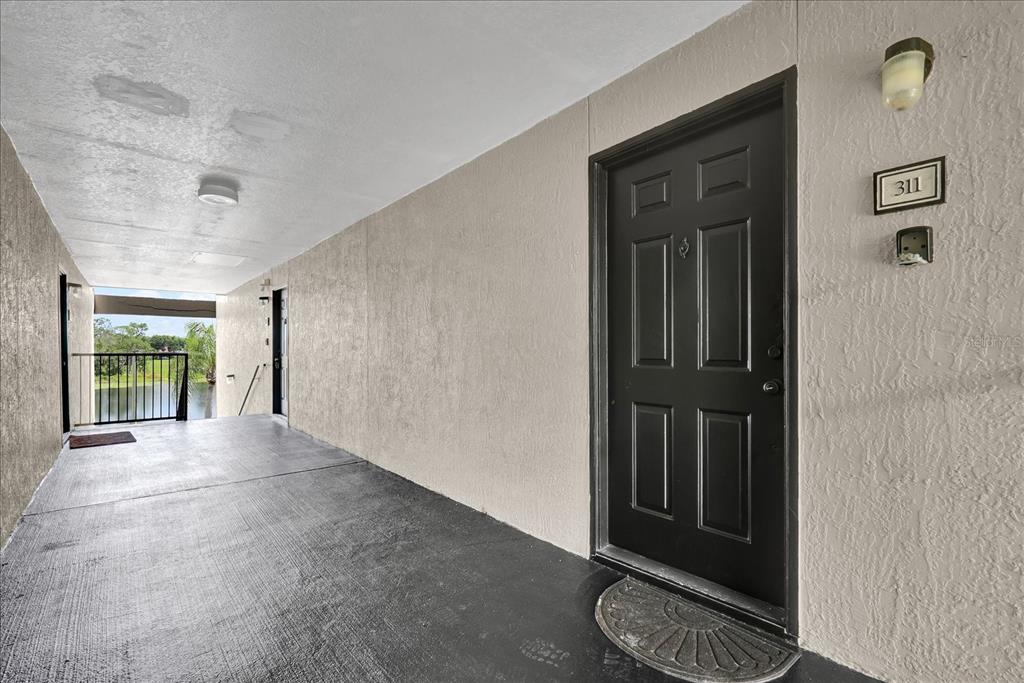A black front door with the number 311 is located on a covered outdoor walkway — 8915 LATREC AVENUE UNIT 2311, ORLANDO, FL