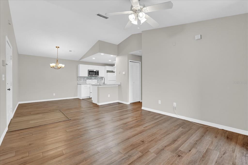 An open-concept living and dining area features light gray walls, wood-look flooring, and a kitchen — 8915 LATREC AVENUE UNIT 2311, ORLANDO, FL