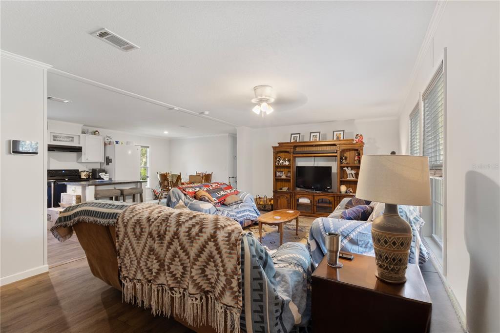 A living room with a large entertainment center, sofa, and an open view of the kitchen — 119 NE 98TH LANE, BRANFORD, FL