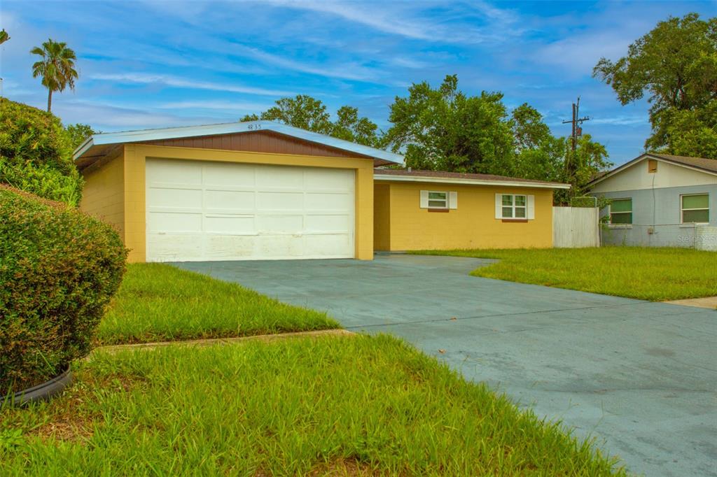 A yellow single-story house with a large white garage door and a paved driveway — 4835 KATHY JO TERRACE, ORLANDO, FL