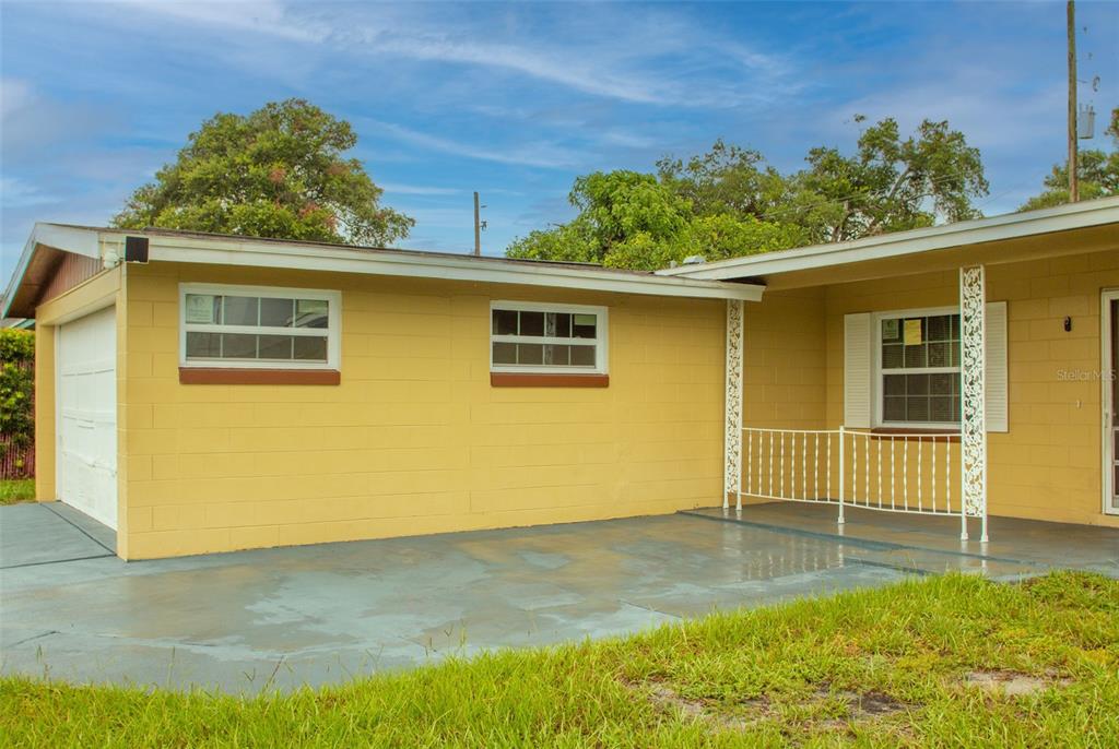 A yellow concrete block house with a garage, a front porch, and a concrete driveway — 4835 KATHY JO TERRACE, ORLANDO, FL