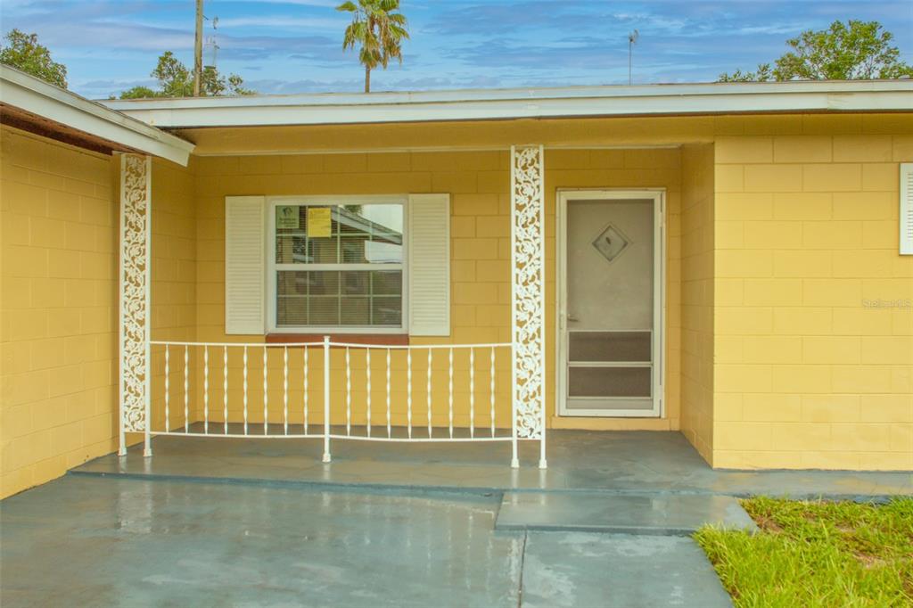 A yellow concrete block house features a front porch with a white metal railing — 4835 KATHY JO TERRACE, ORLANDO, FL