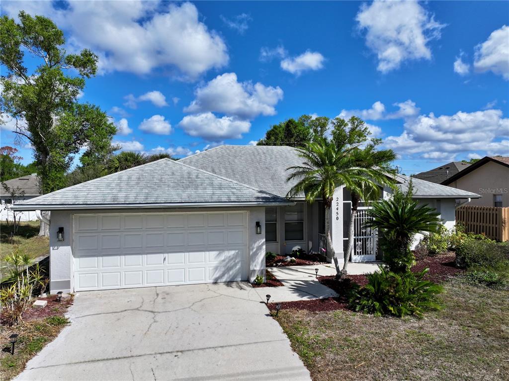 A single-story house with a white garage, a concrete driveway, and palm trees in front — 22450 PEACHLAND BOULEVARD, PORT CHARLOTTE, FL