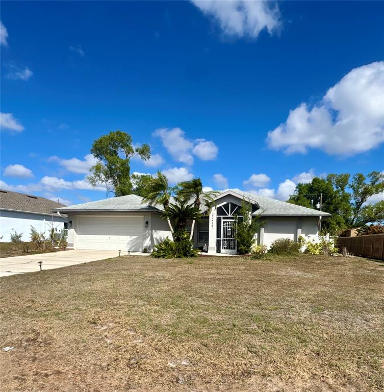 A single-story house with a white garage, a front entryway, and palm trees — 22450 PEACHLAND BOULEVARD, PORT CHARLOTTE, FL
