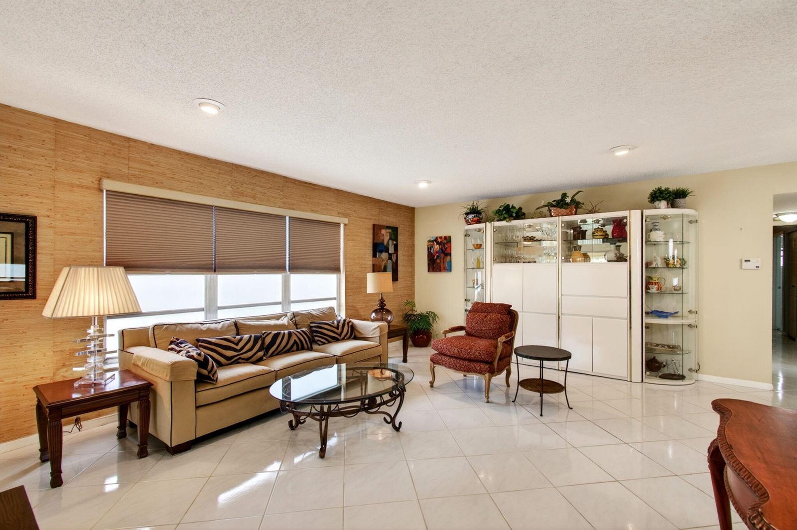 A living room features a beige sofa, a glass coffee table, and light-colored tile flooring — 14290 Nesting Way # A, Delray Beach FL 33484, DELRAY BEACH, FL