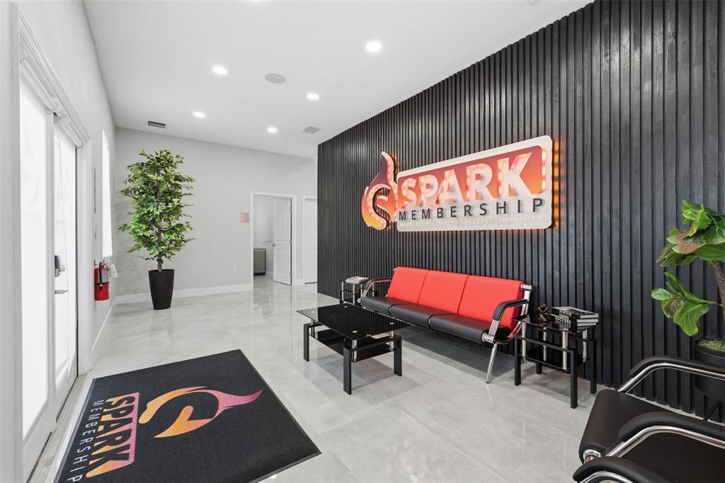 A modern office lobby features a black slatted accent wall, a red sofa, and tile flooring — 13003 W LINEBAUGH AVENUE, TAMPA, FL