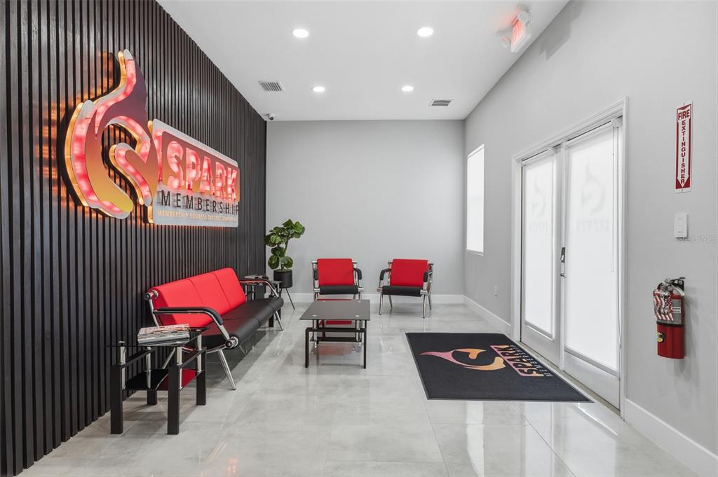 A modern office waiting area features a branded wall, red seating, and tile flooring — 13003 W LINEBAUGH AVENUE, TAMPA, FL