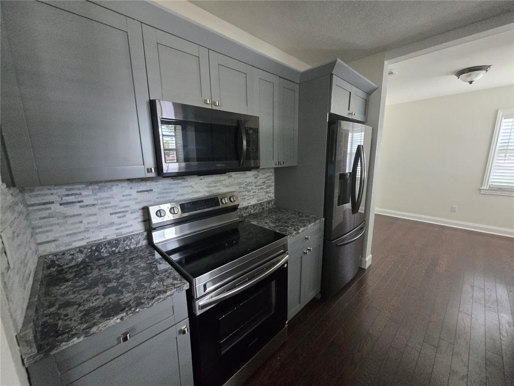 A kitchen features gray cabinets, stainless steel appliances, and a patterned stone countertop — 300 E IDLEWILD AVENUE, TAMPA, FL
