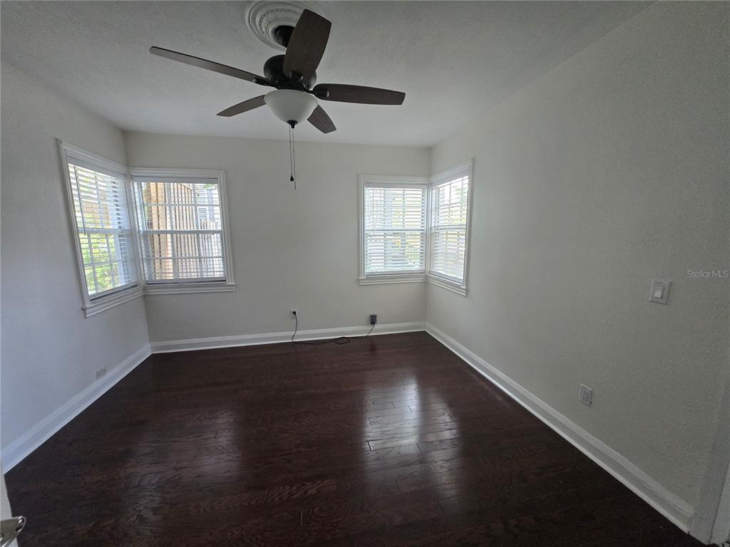 An empty room features dark hardwood floors, white walls, and a ceiling fan — 300 E IDLEWILD AVENUE, TAMPA, FL